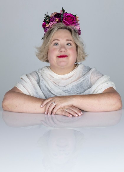 Photo of Bonnie Smith Whitehouse. Bonnie is wearing a flower crown and a white top, smiling at the camera