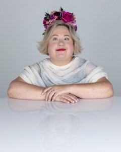 Photo of Bonnie Smith Whitehouse. Bonnie is wearing a flower crown and a white top, smiling at the camera